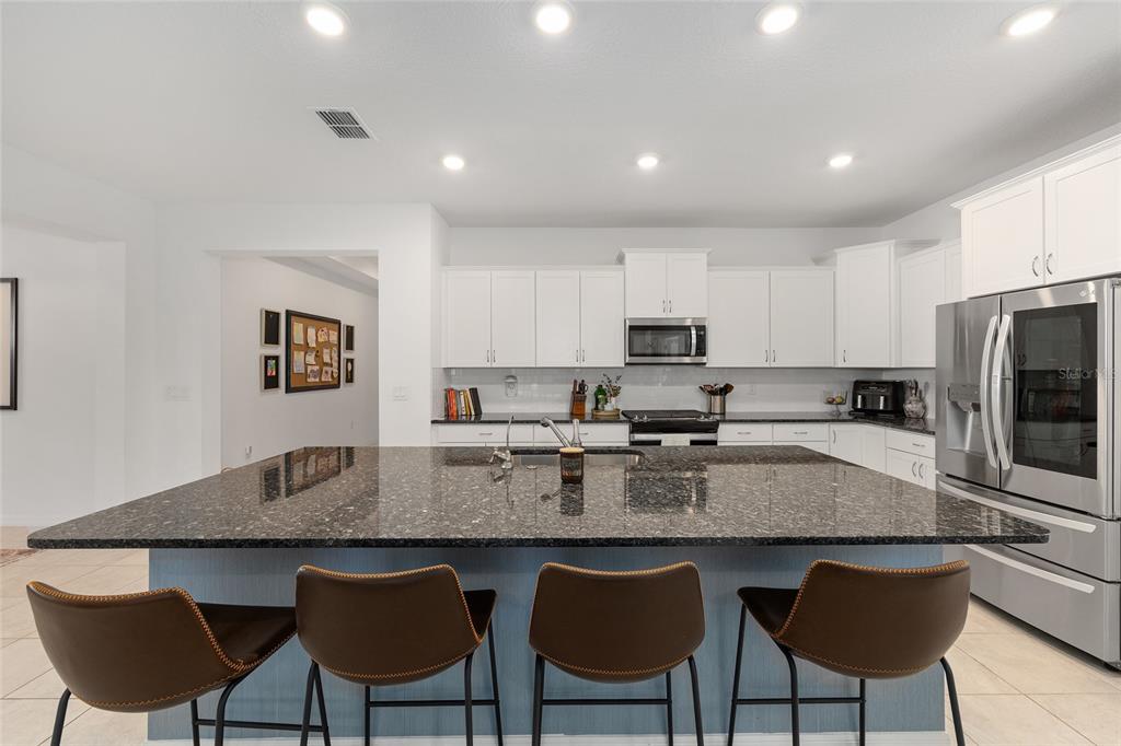 7431 Southwest 65th Place Road Ocala, FL 34474 - Photo 6 of 49 a kitchen with granite countertop a table chairs microwave and cabinets