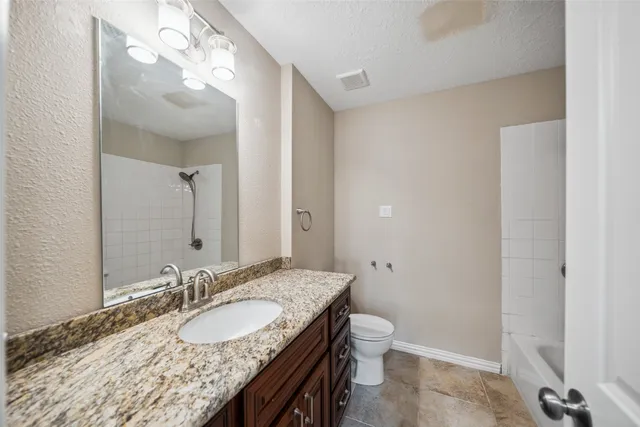 a bathroom with a granite countertop sink a toilet and a mirror