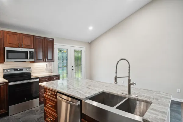 a kitchen with granite countertop a sink and a stove top oven with wooden floor