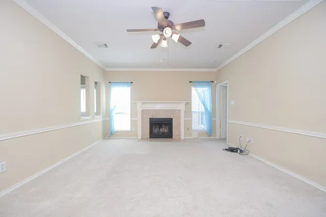 a view of a livingroom with a fireplace a ceiling fan and windows
