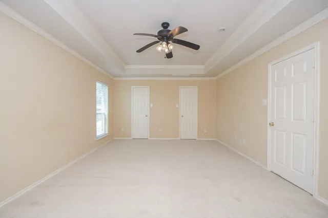 an empty room with ceiling fan and window