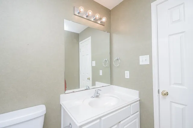 a bathroom with a sink a toilet and a mirror