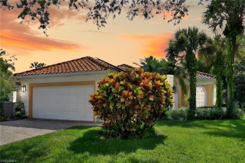 Mediterranean / spanish-style home featuring a front lawn, a tile roof, driveway, and stucco siding