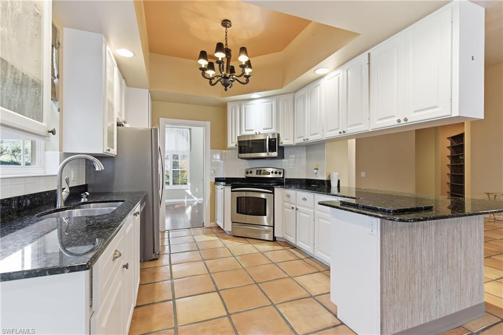 5902 Bermuda Lane Naples, FL 34119 - Photo 9 of 18 a kitchen with granite countertop a sink cabinets stainless steel appliances and a counter top space