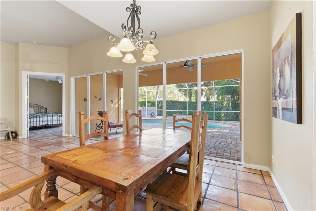 5902 Bermuda Lane Naples, FL 34119 - Photo 10 of 18 a dining room with wooden floor a chandelier a wooden table and chairs