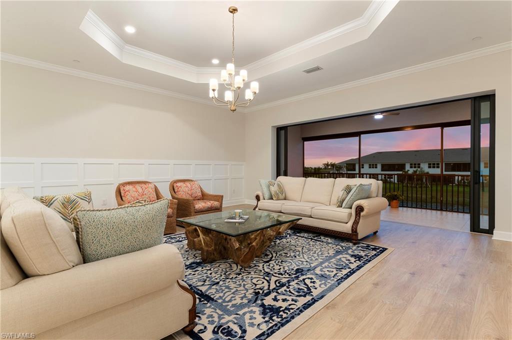 15328 Lucerna Street, Unit 202 Naples, FL 34114 - Photo 6 of 32 a living room with furniture a chandelier and a flat screen tv