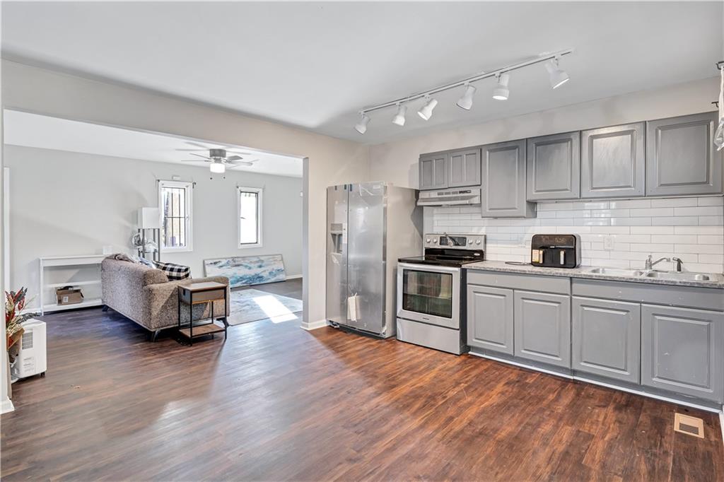 1920 Moores Mill Road Northwest Atlanta, GA 30318 - Photo 24 of 33 a kitchen with stainless steel appliances granite countertop a refrigerator oven a sink dishwasher and white cabinets with wooden floor