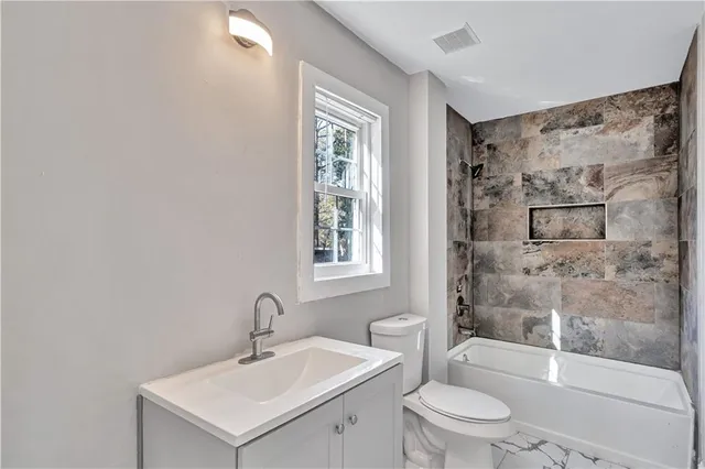 a bathroom with a bathtub shower sink mirror and toilet