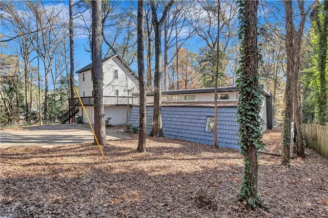 a backyard of a house with large trees and table