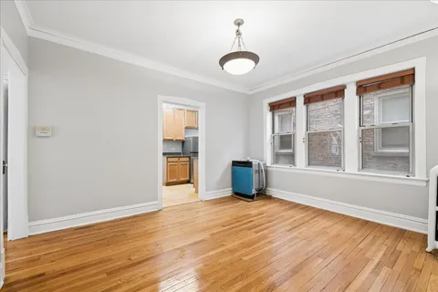 a view of an empty room with a window and wooden floor