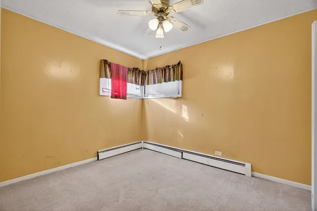 an empty room with a ceiling fan and window