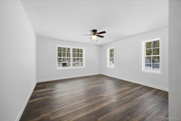 an empty room with wooden floor ceiling fan and windows