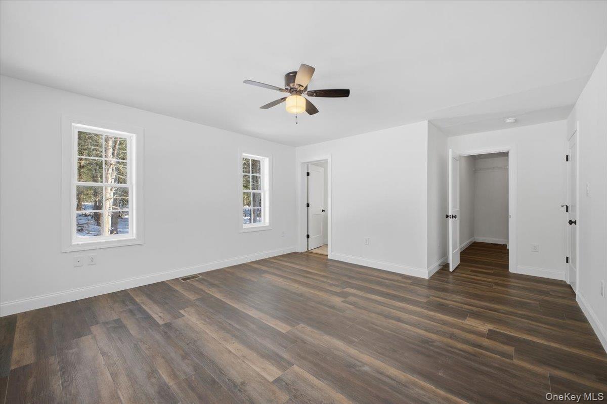 196 Fawn Hill Road Prattsville, NY 12468 - Photo 25 of 45 an empty room with wooden floor ceiling fan and windows