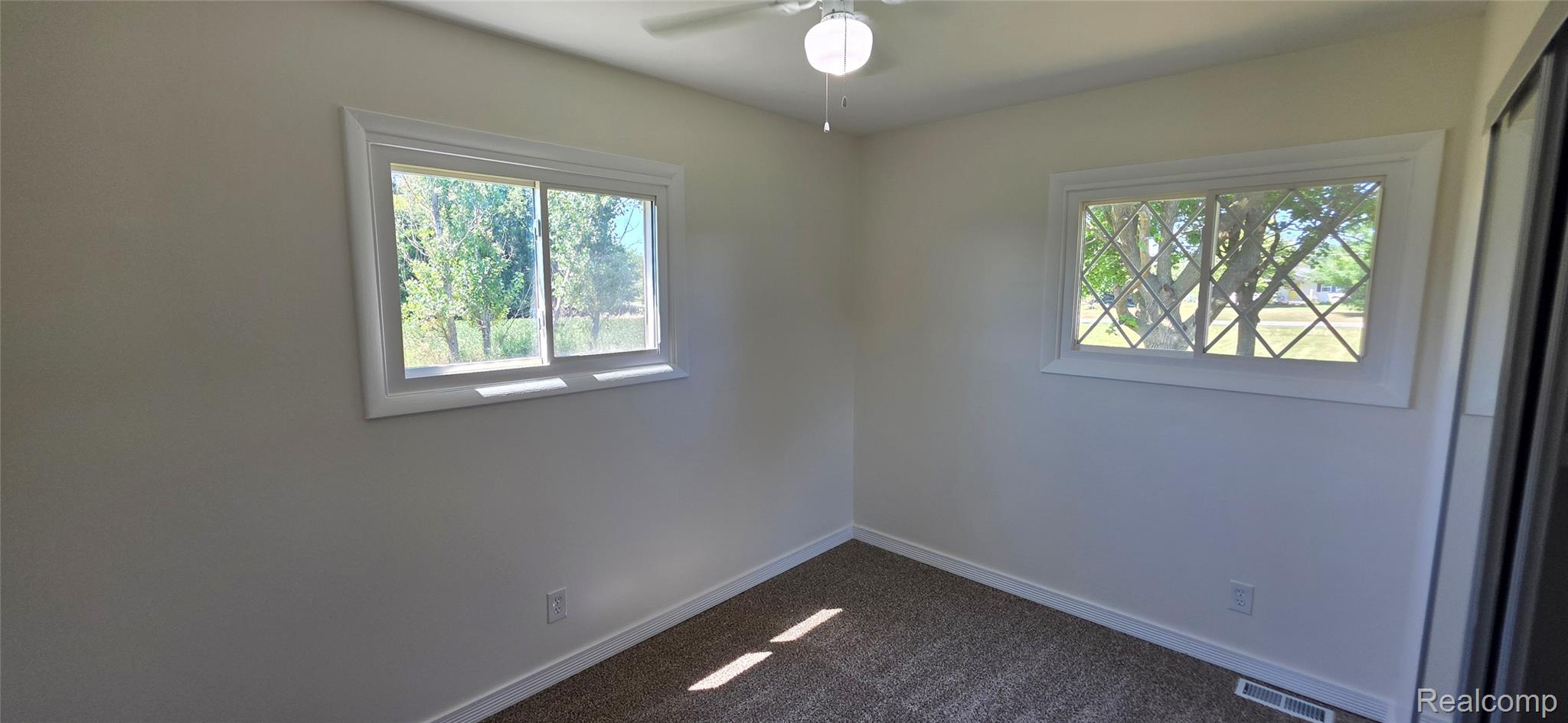 4363 West Dodge Road Clio, MI 48420 - Photo 28 of 52 Carpeted room with white walls, two windows, and a ceiling fan with light fixture