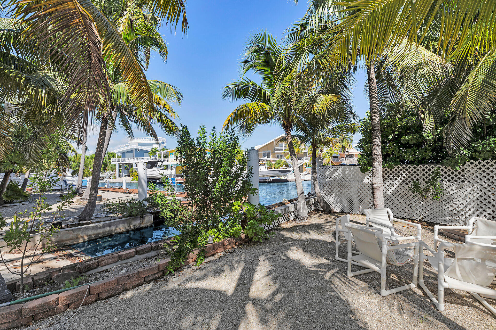 Undisclosed Address Key Largo, FL 33037 - Photo 18 of 69 a backyard of a house with table and chairs under an umbrella