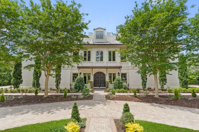 a view of a white house with a big yard and large trees