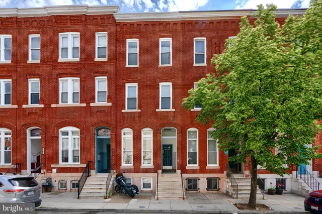 a front view of a building with lots of trees and plants