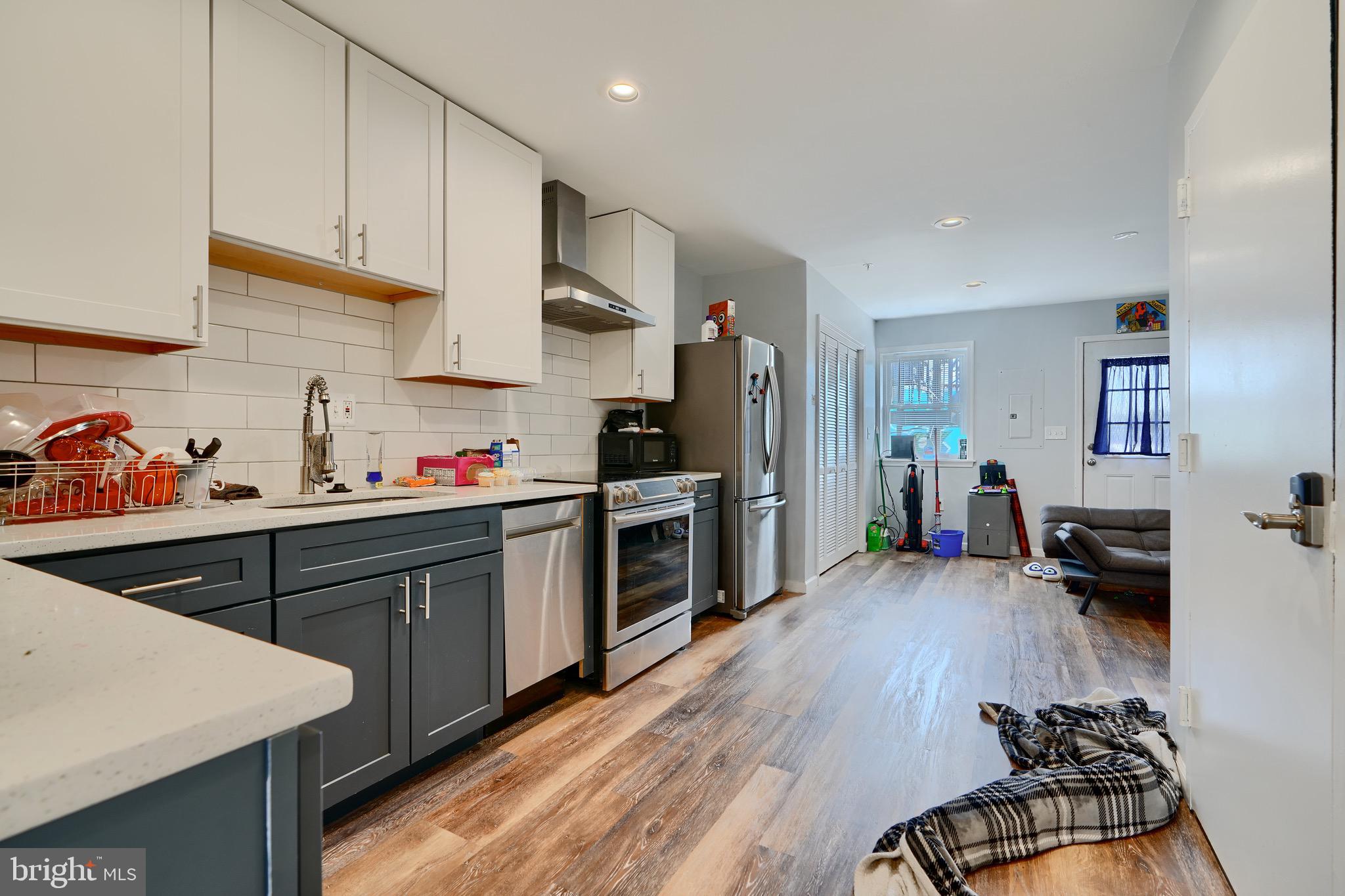 1729 Guilford Avenue, Unit 2 Baltimore, MD 21202 - Photo 4 of 15 a kitchen with granite countertop a stove top oven a sink dishwasher and a refrigerator with wooden floor