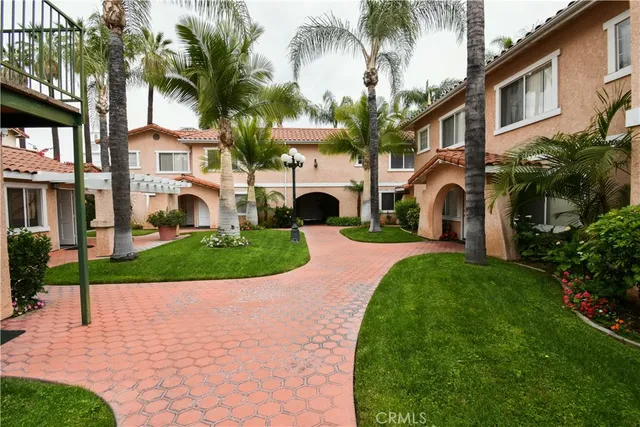 a front view of a house with a garden and palm trees
