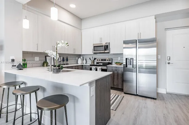 a kitchen with kitchen island a refrigerator a stove a sink and chairs