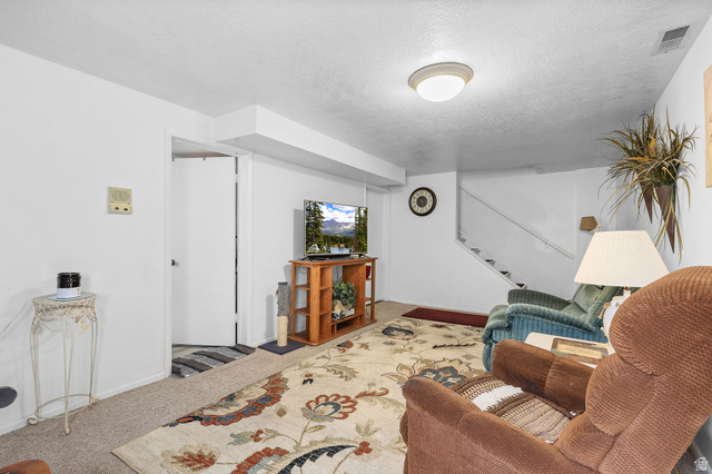 1120 Canyon Road, Unit 38 Ogden, UT 84404 - Photo 21 of 24 Carpeted living room featuring stairway and a textured ceiling