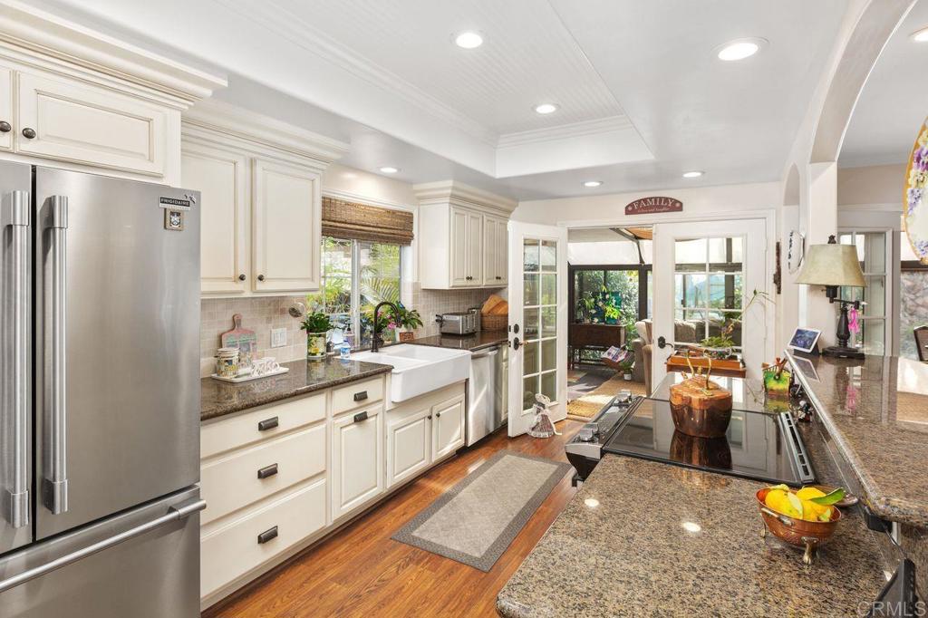 3433 Royal Road Vista, CA 92084 - Photo 15 of 45 a kitchen with stainless steel appliances granite countertop a refrigerator a stove and white cabinets with wooden floor