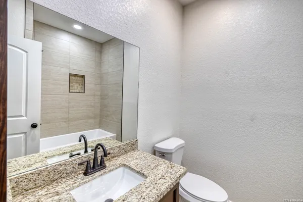 a bathroom with a granite countertop sink a toilet and mirror