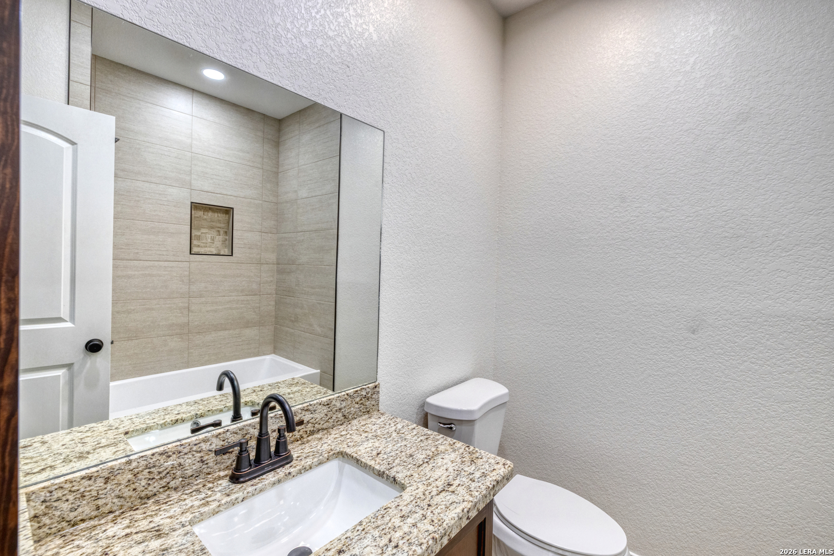 207 Riverside Drive Uvalde, TX 78801 - Photo 15 of 37 a bathroom with a granite countertop sink a toilet and mirror