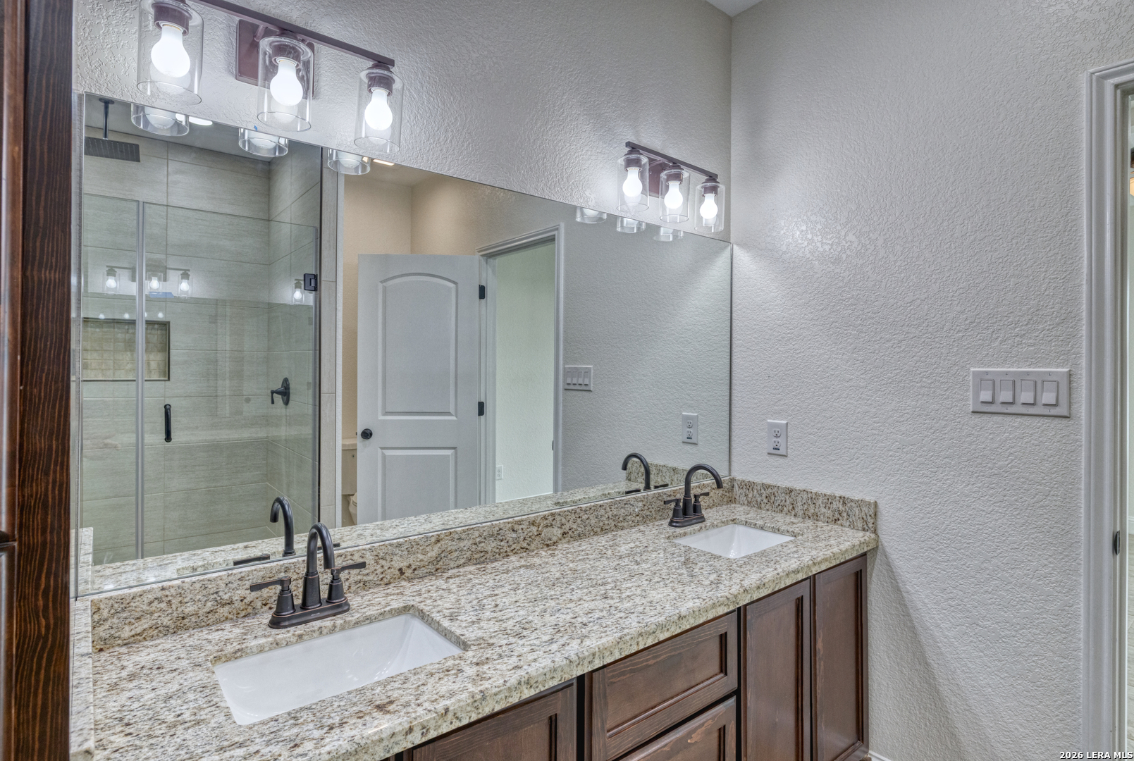 207 Riverside Drive Uvalde, TX 78801 - Photo 32 of 37 a bathroom with a granite countertop sink a mirror and shower