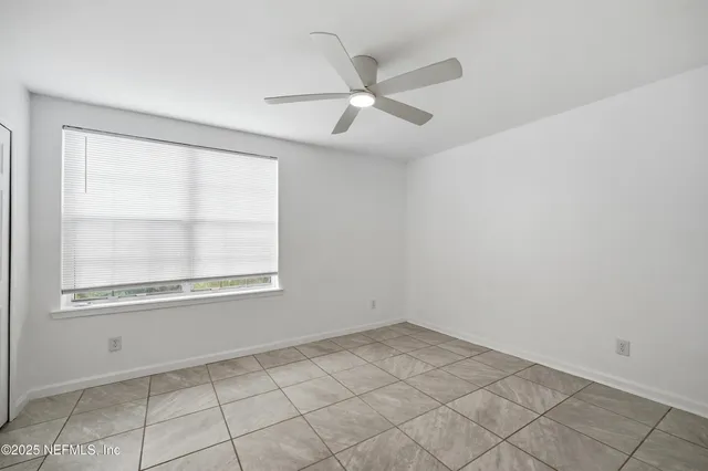 an empty room with windows and fan