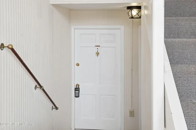a view of a hallway with a white door and stairs