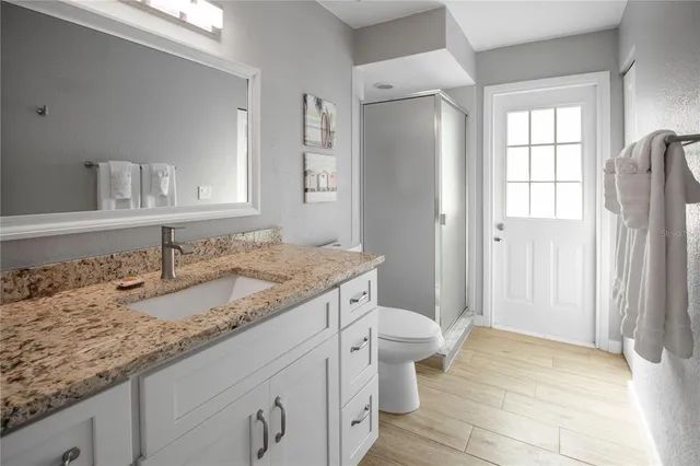 a bathroom with a granite countertop sink toilet and shower