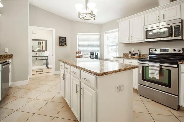 a kitchen with stainless steel appliances granite countertop a stove a sink and a microwave