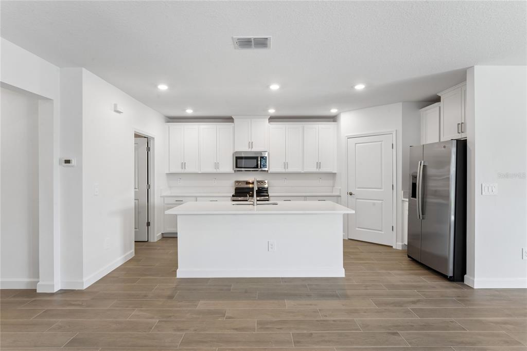 6692 Homebound Way New Port Richey, FL 34653 - Photo 12 of 47 a large kitchen with stainless steel appliances a refrigerator stove top oven and cabinets