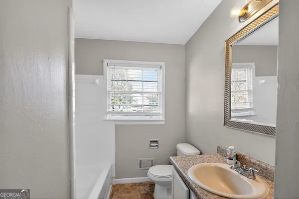 a bathroom with a toilet sink vanity granite and mirror