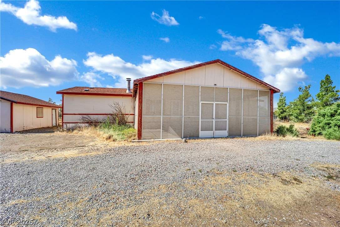 4361 Maple Road Pahrump, NV 89048 - Photo 36 of 46 A utilitarian structure with a screened front stands under a vast, cloud-dappled sky.
