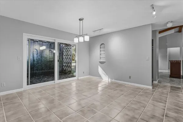 a view of an empty room with window and chandelier fan