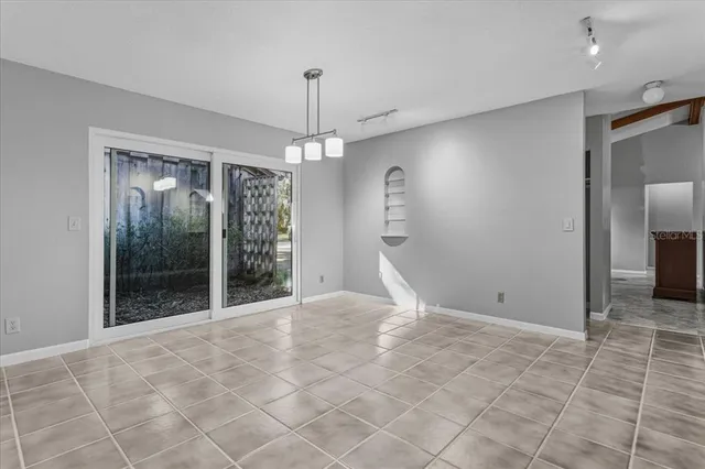 a view of an empty room with window and chandelier fan