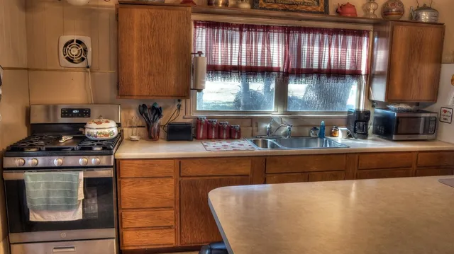 a kitchen with granite countertop a stove a sink and a cabinets