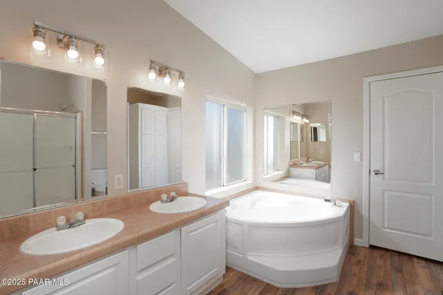 a bathroom with a sink double vanity granite tub shower and a mirror