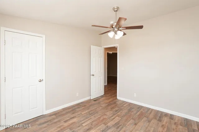 an empty room with wooden floor ceiling fan and windows