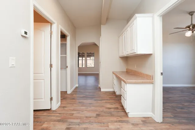 a view of empty room with wooden floor and fan