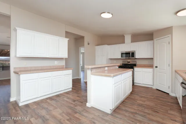 a kitchen with granite countertop a stove top oven a sink dishwasher and a refrigerator with wooden floor