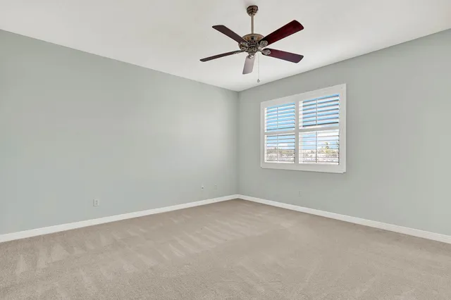 an empty room with a window and a fan