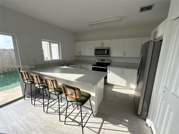 a kitchen with stainless steel appliances a table chairs and a refrigerator