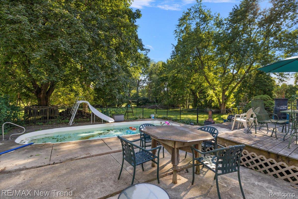1450 Lenox Road Bloomfield Hills, MI 48304 - Photo 65 of 79 Expansive concrete patio with a built-in swimming pool and a surrounding black metal fence