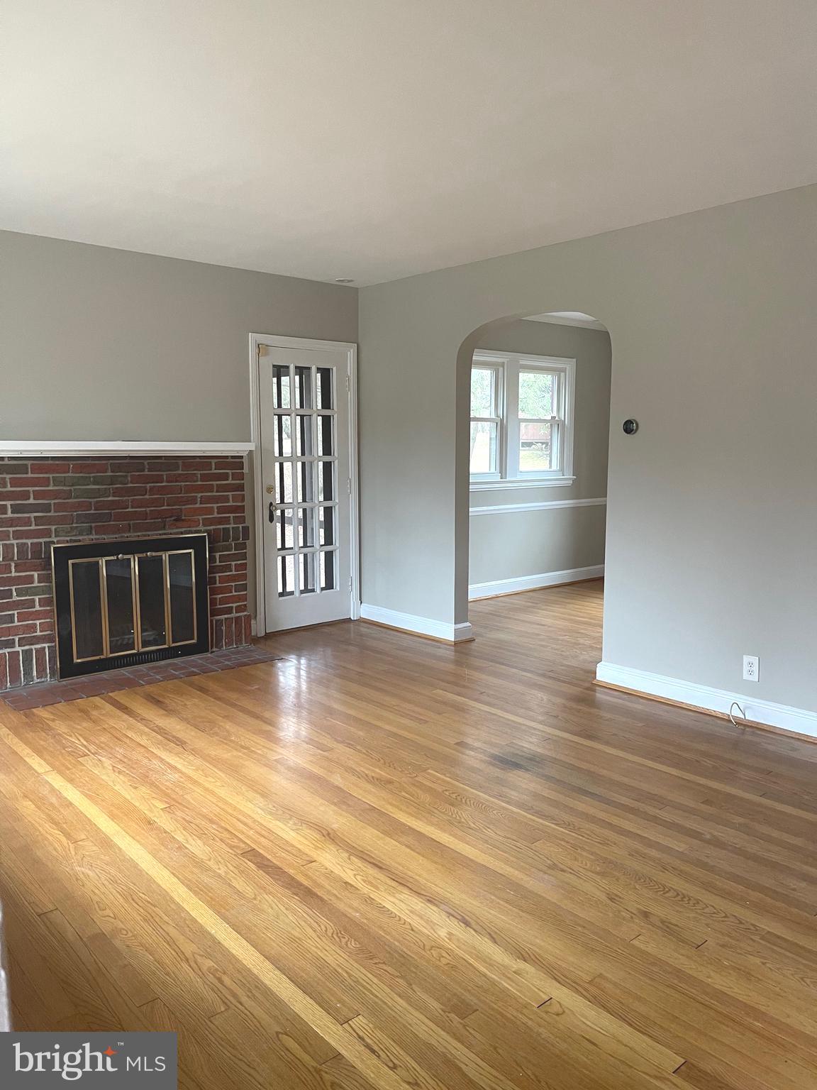 9803 Forest Grove Drive Silver Spring, MD 20902 - Photo 3 of 24 an empty room with wooden floor and fireplace