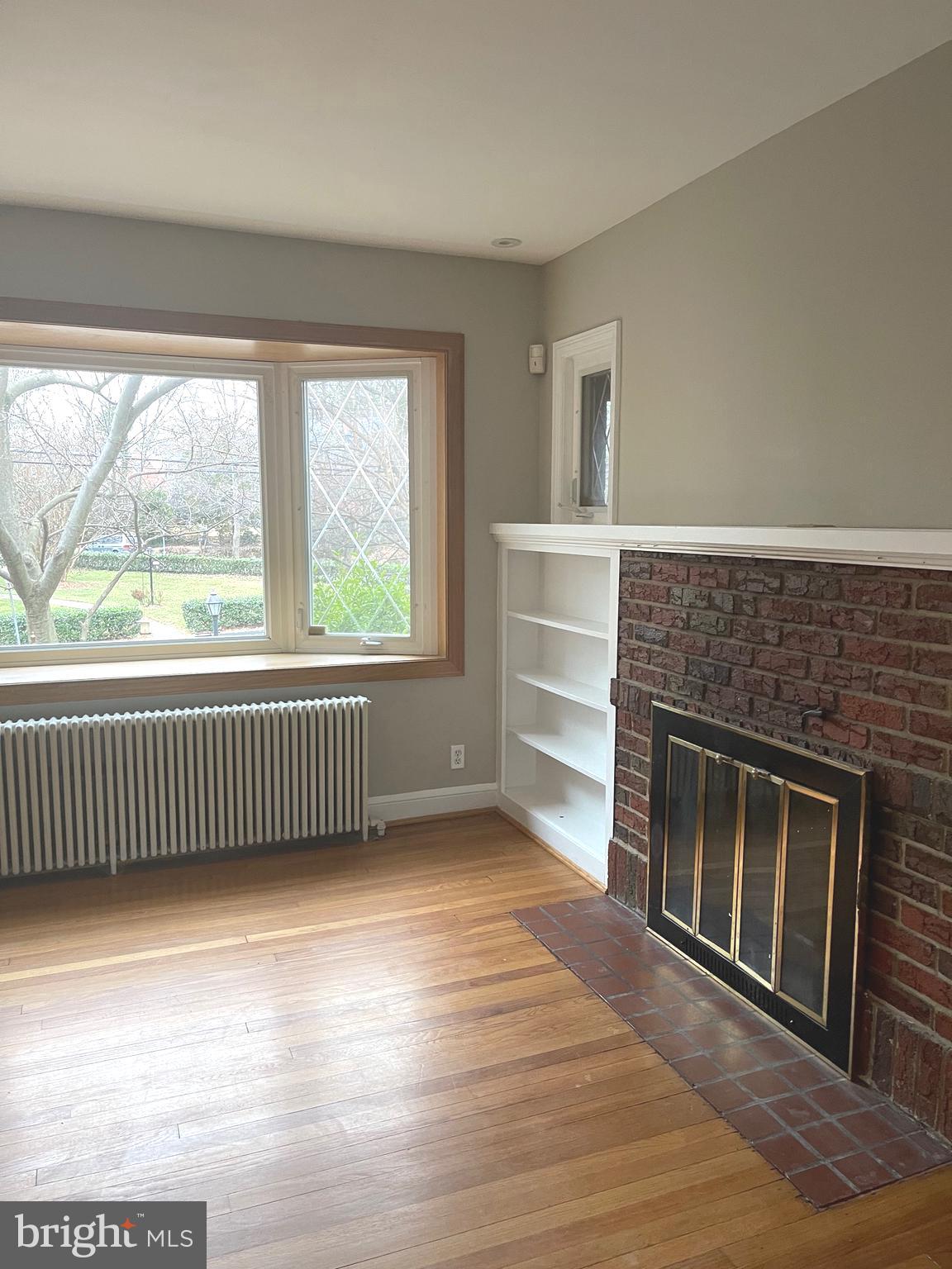 9803 Forest Grove Drive Silver Spring, MD 20902 - Photo 7 of 24 a view of empty room with wooden floor and fireplace
