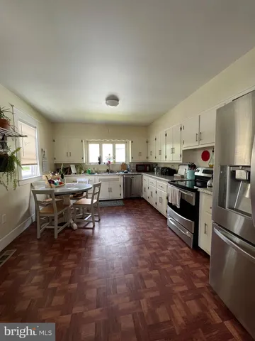 a kitchen with stainless steel appliances kitchen island granite countertop a stove top oven a sink a dining table and chairs