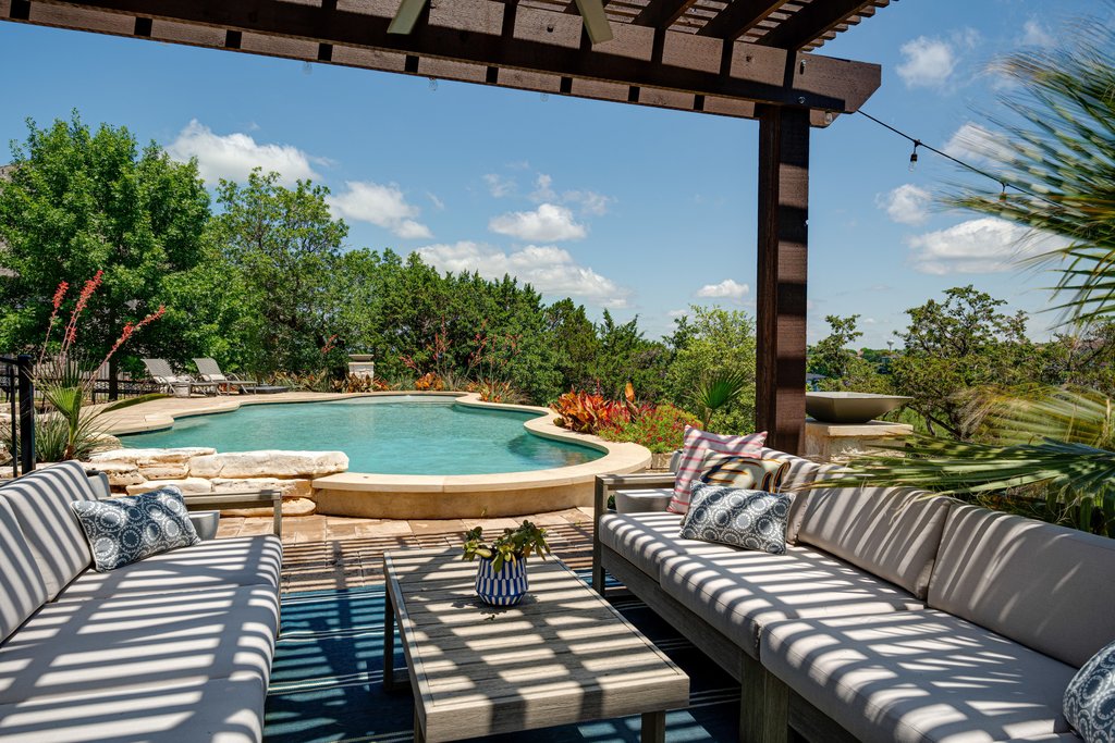 203 Lodestone Lane Austin, TX 78738 - Photo 39 of 40 Outdoor living area featuring a custom swimming pool with natural stone coping, a large wooden pergola, and lush surrounding landscaping